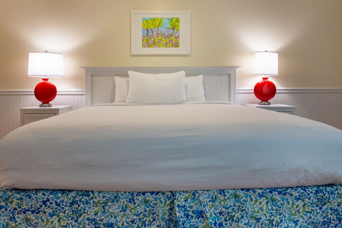 a bed with white sheets and a red lamp on the side