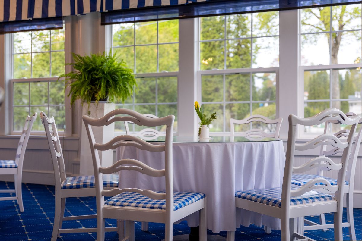 a table with chairs and a plant in front of windows