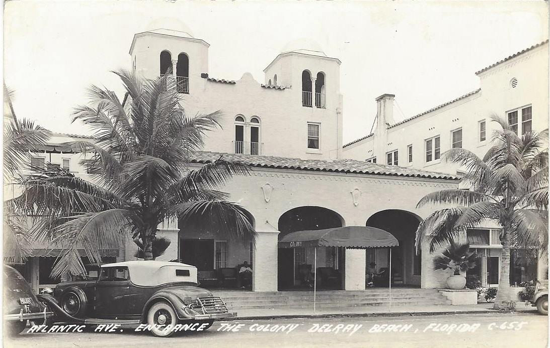 a black and white photo of a building with palm trees