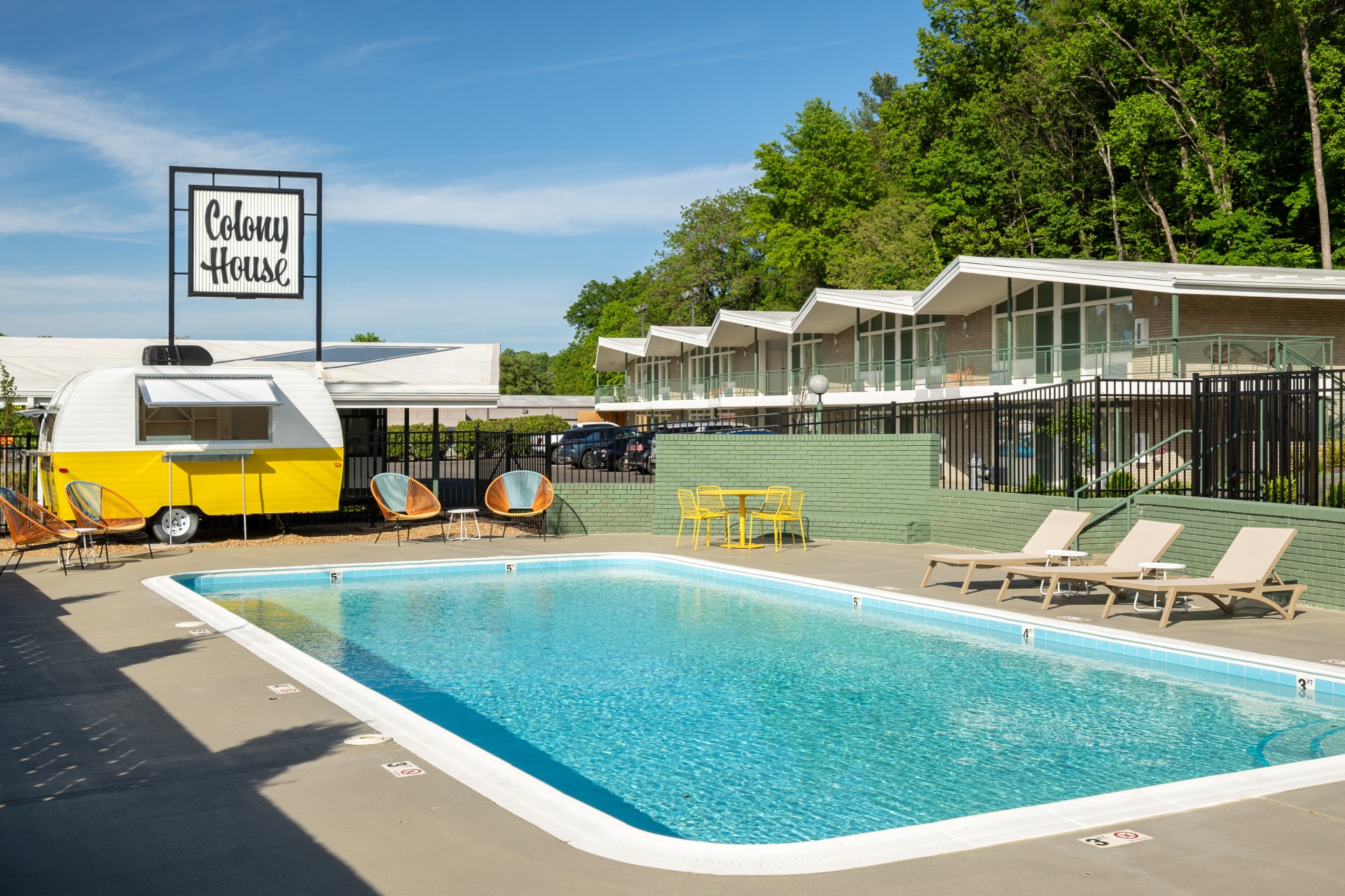 a pool with chairs and a fence in front of a building