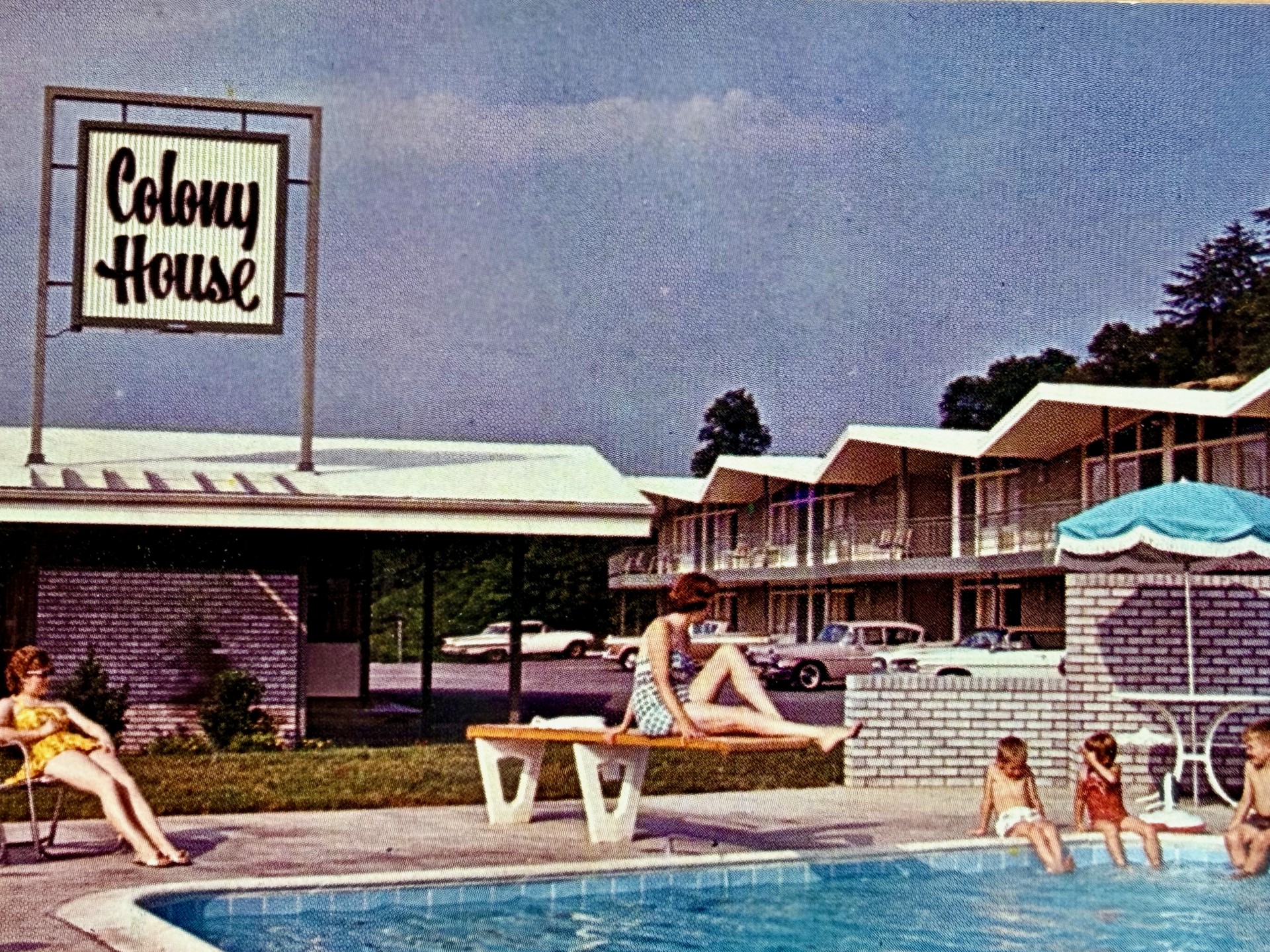 a group of people sitting on a bench by a pool
