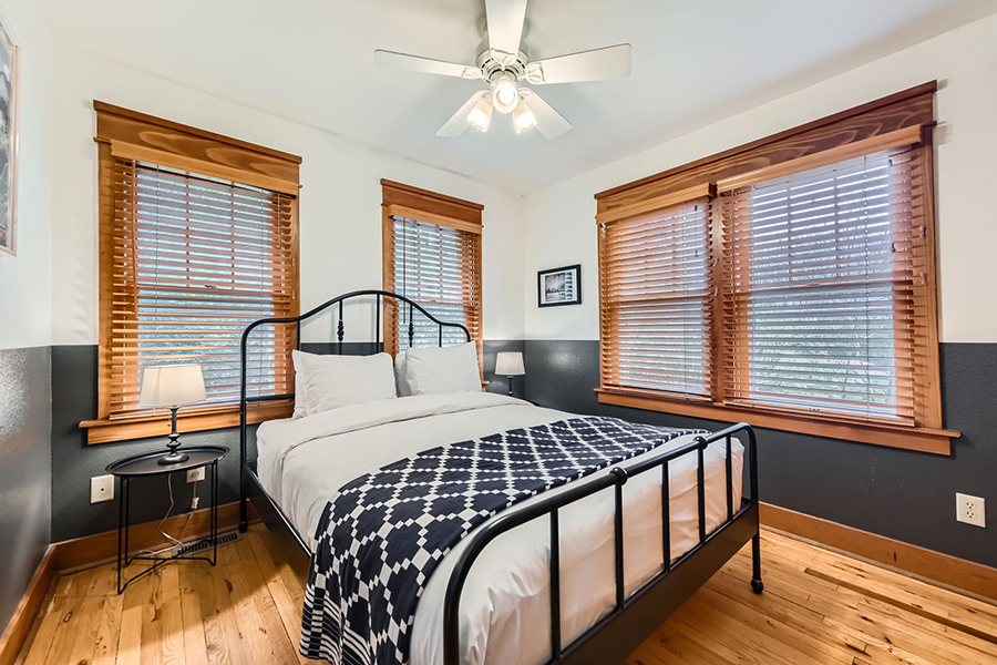 a bed with a fan in the window