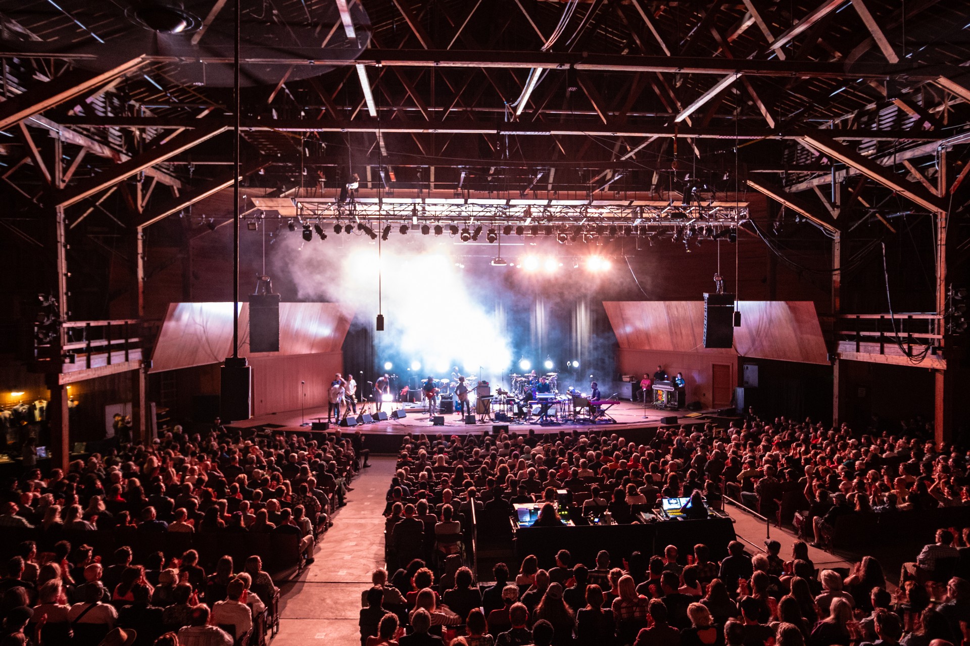 a group of people on stage with a band on stage with Roundhouse in the background