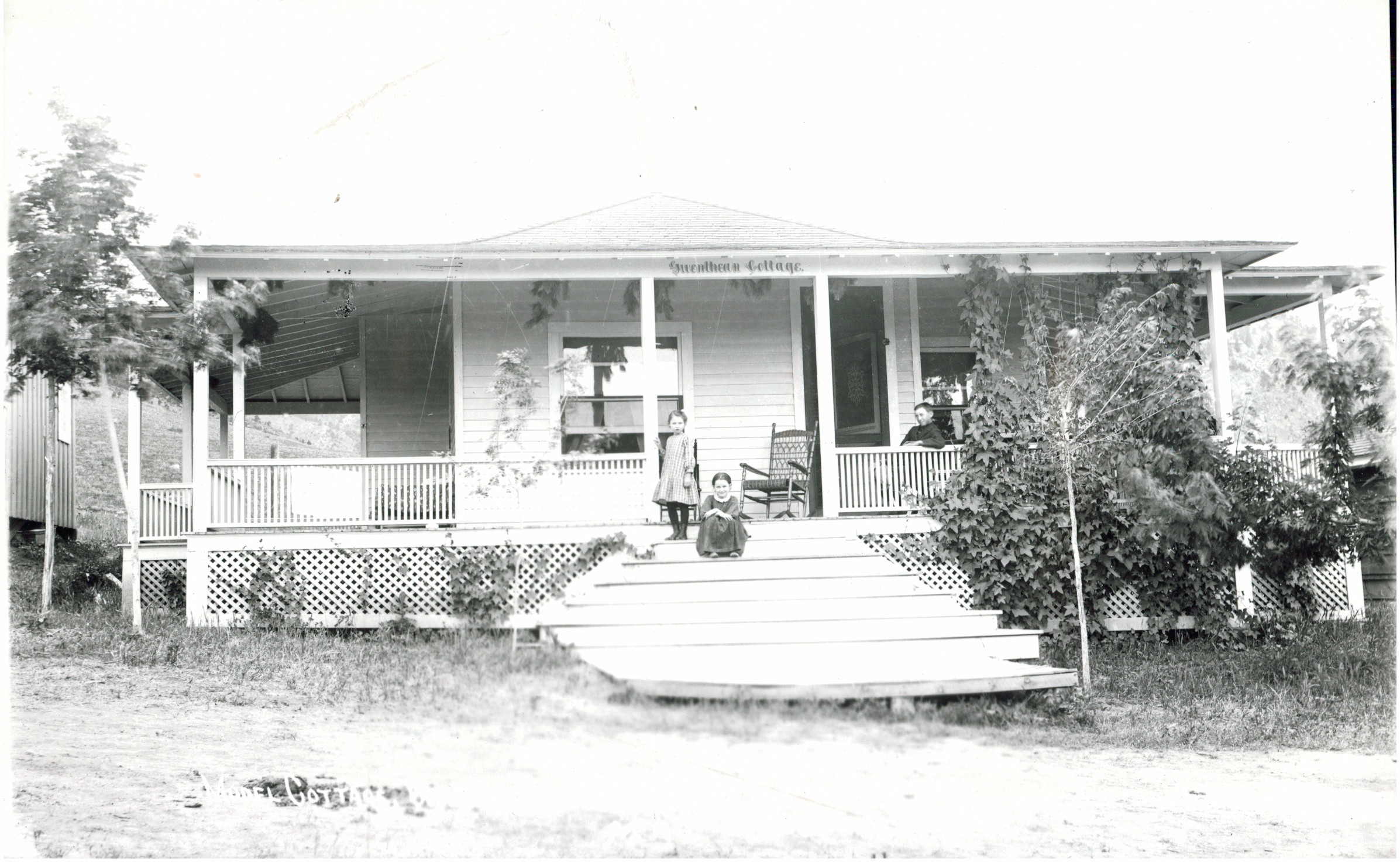 a black and white photo of a house with a porch and a couple of kids