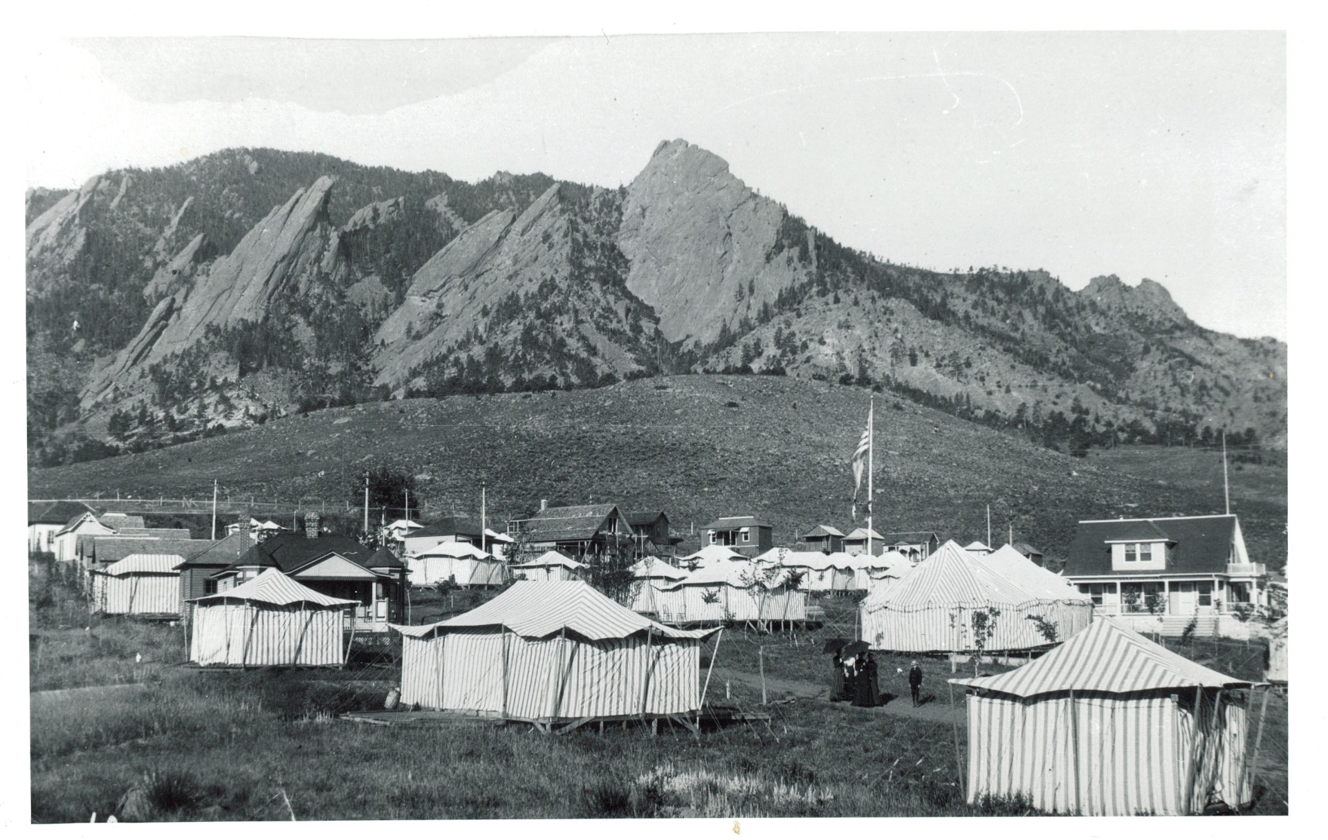 a group of tents in a field with mountains in the background
