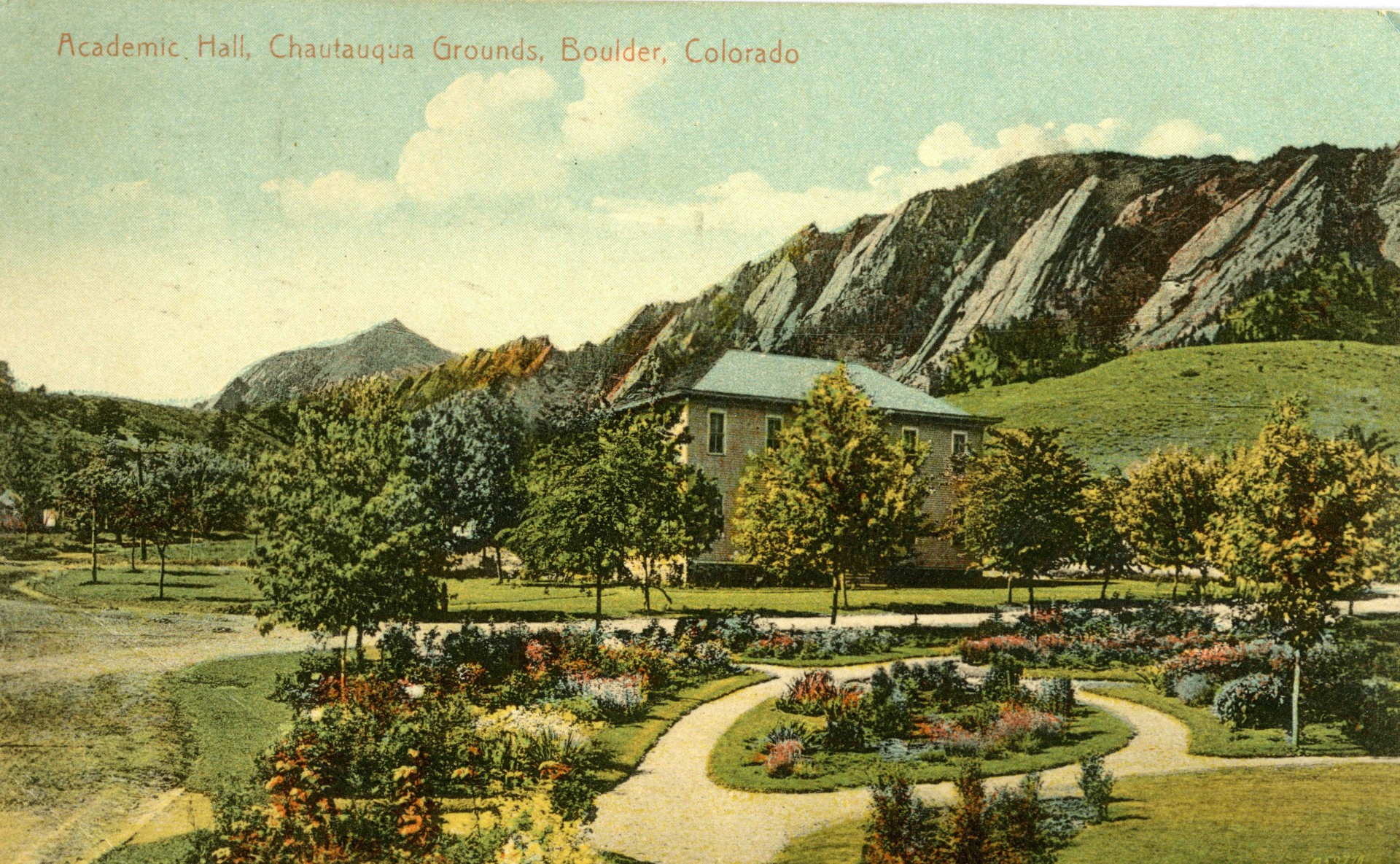 a garden with a house and mountains in the background