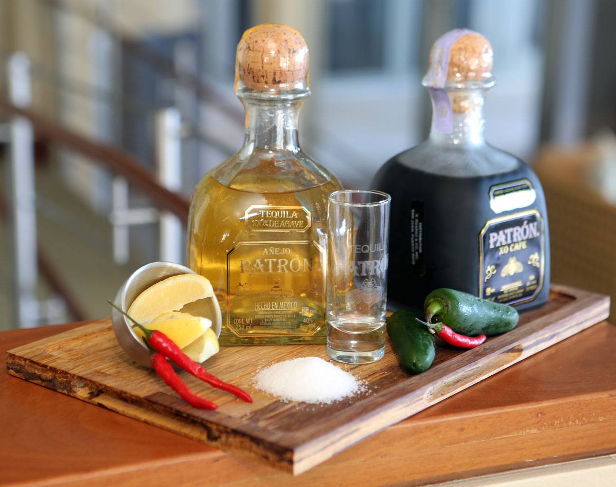 a bottle of tequila with a shot glass and a couple of lemons and a salt shaker