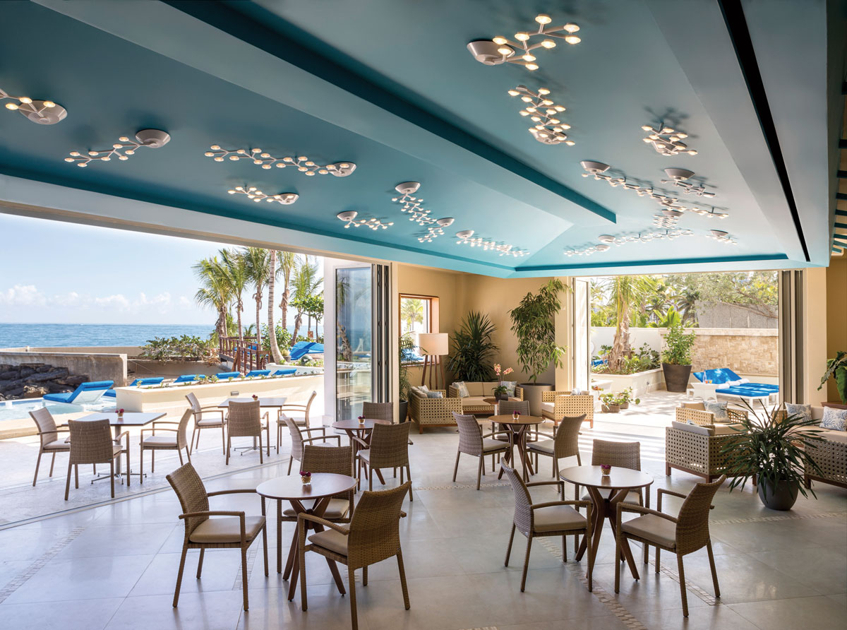 a room with tables and chairs and a pool in the background