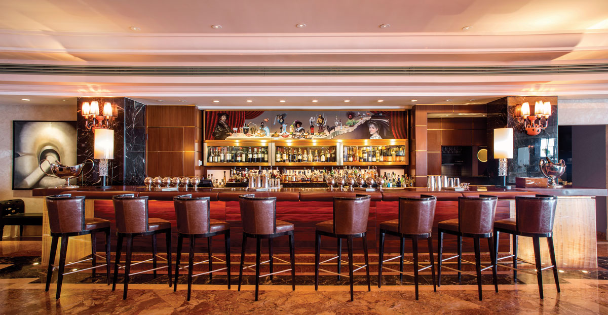 a bar with many chairs and a bar with many bottles