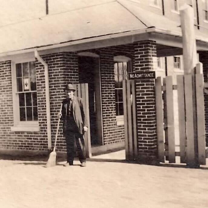 a man holding a broom in front of a building