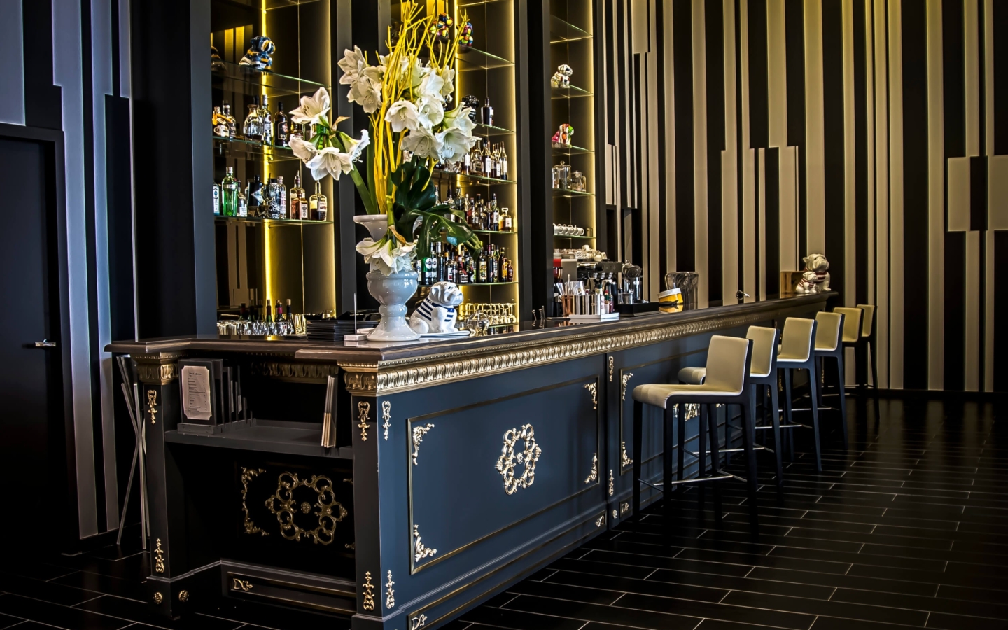 a bar with a vase of flowers and shelves of liquor