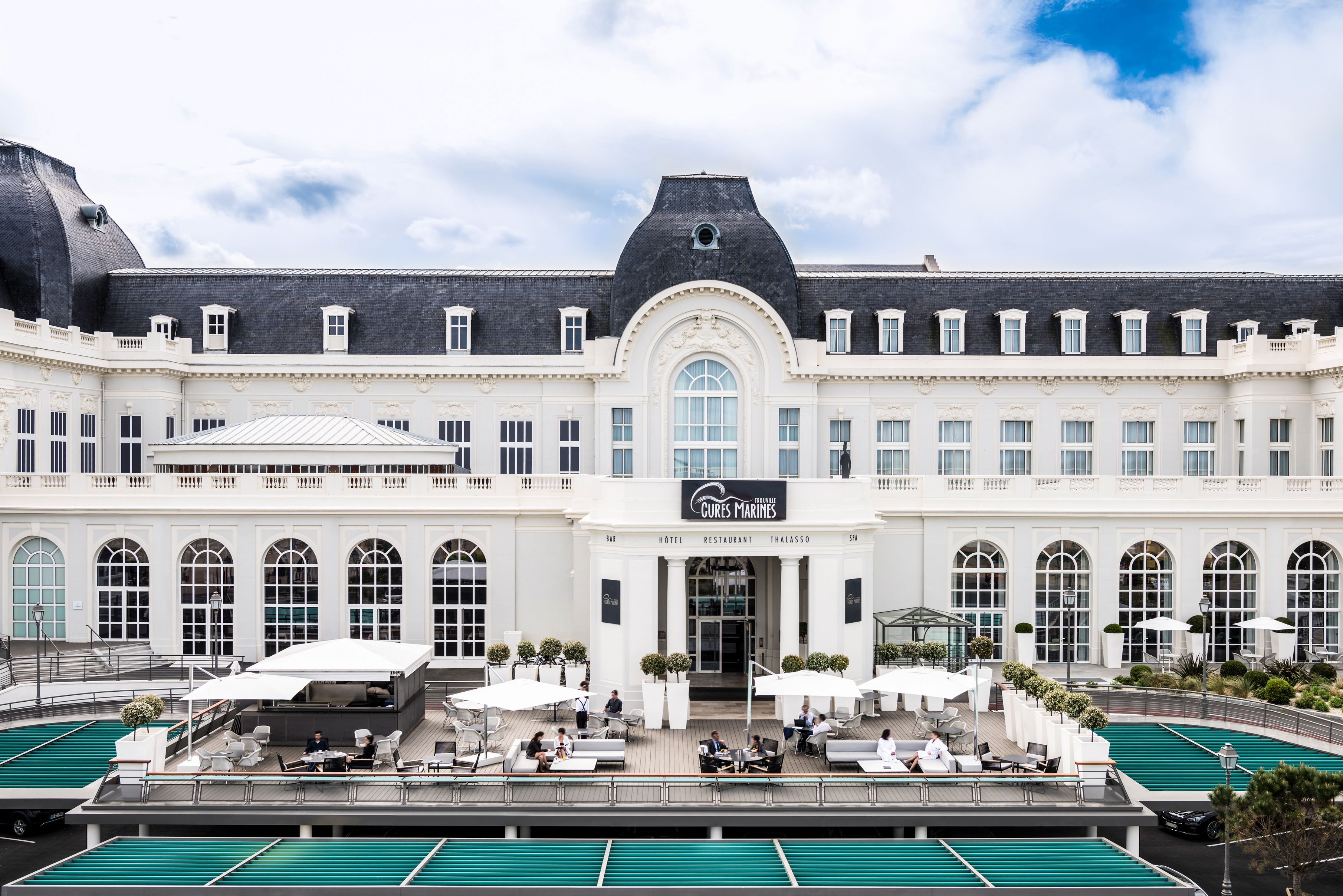 a building with a pool and people sitting outside