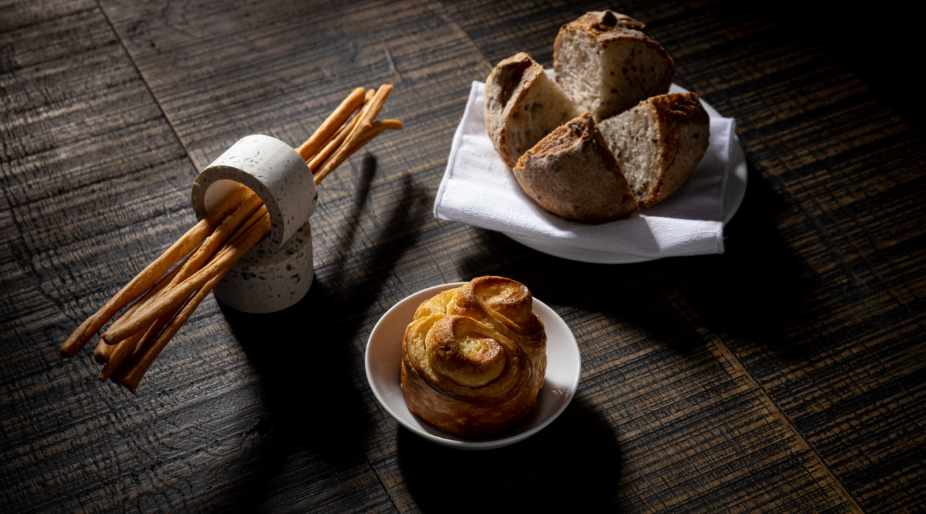 a plate of bread and a roll on a white napkin