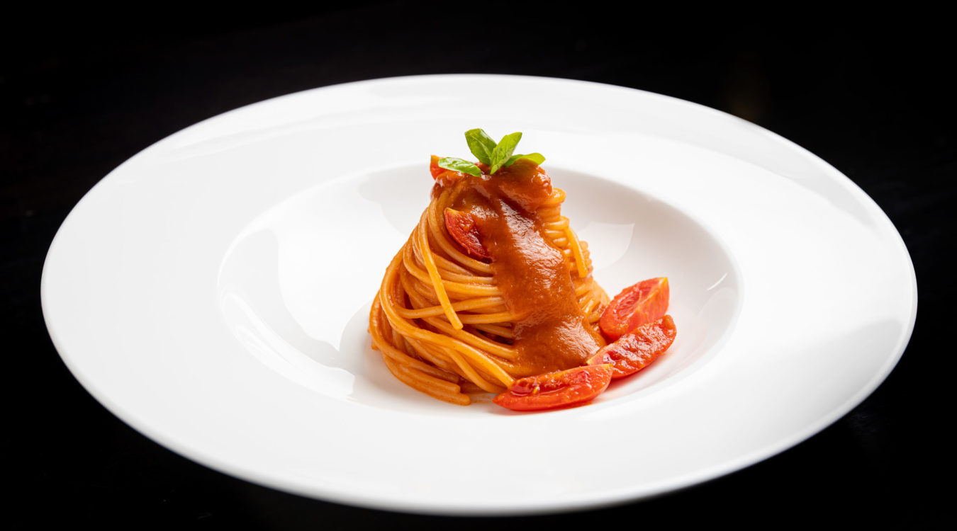 a plate of spaghetti with sauce and tomatoes