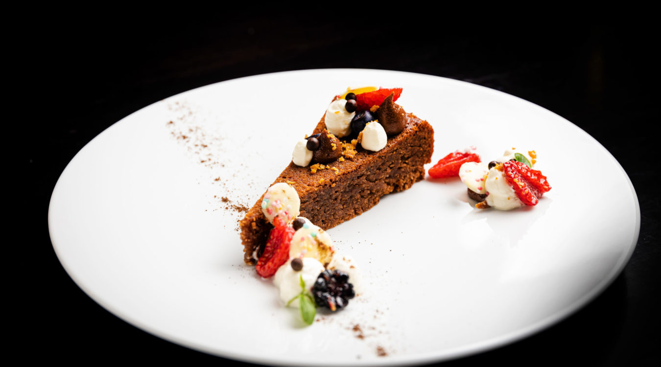 a piece of cake with whipped cream and strawberries on a white plate