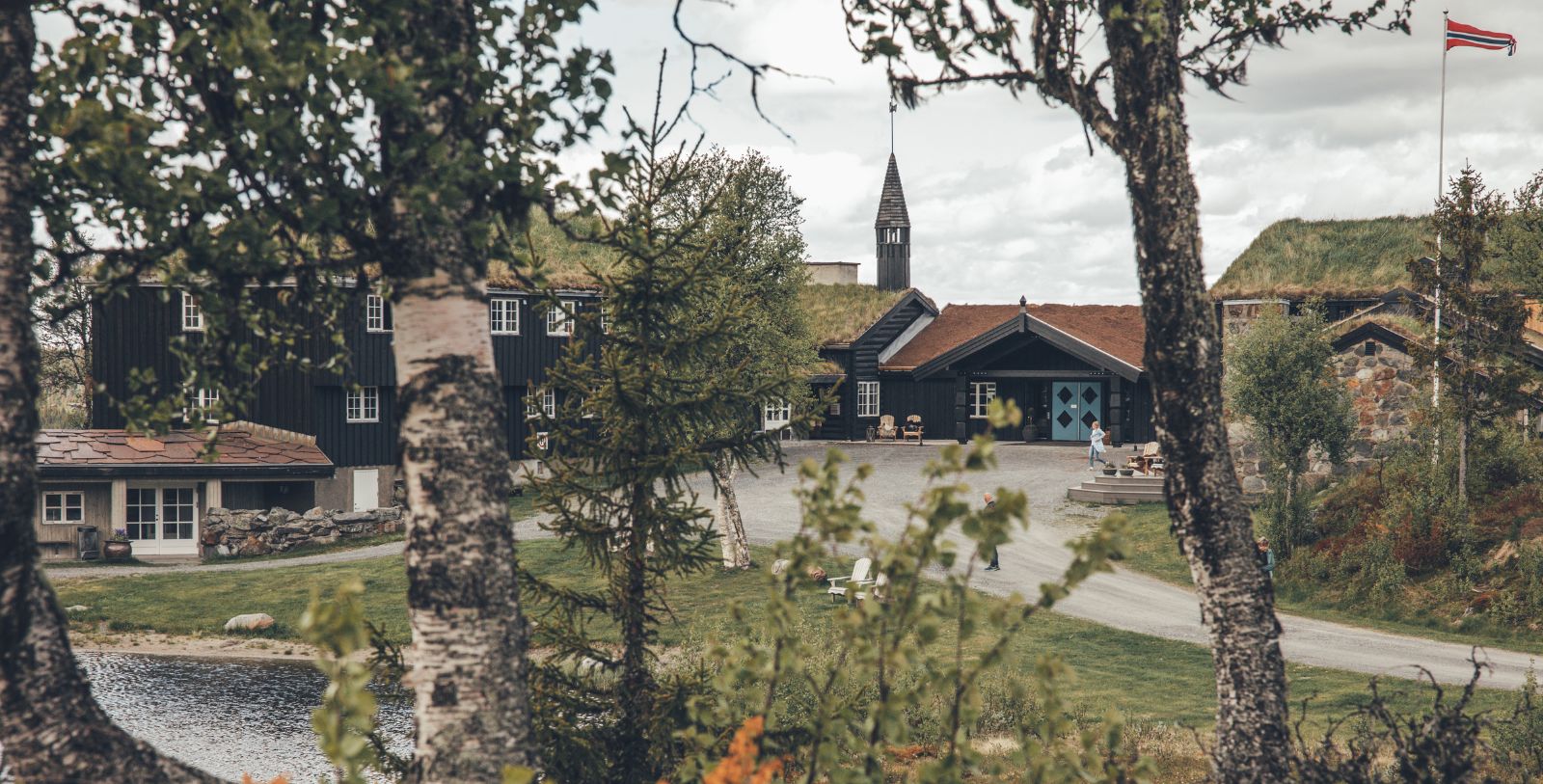a building with grass roof and a church in the background