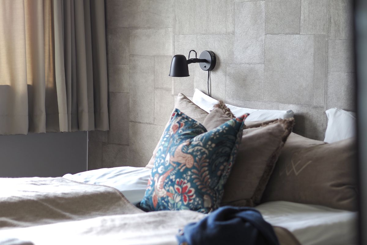 a bed with pillows and a lamp on the wall