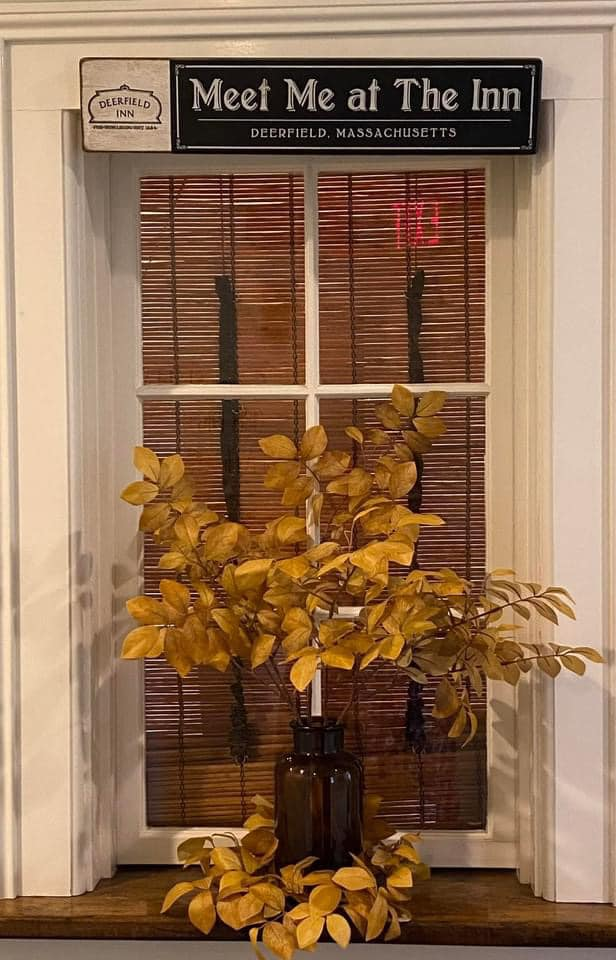 a vase with leaves in front of a window