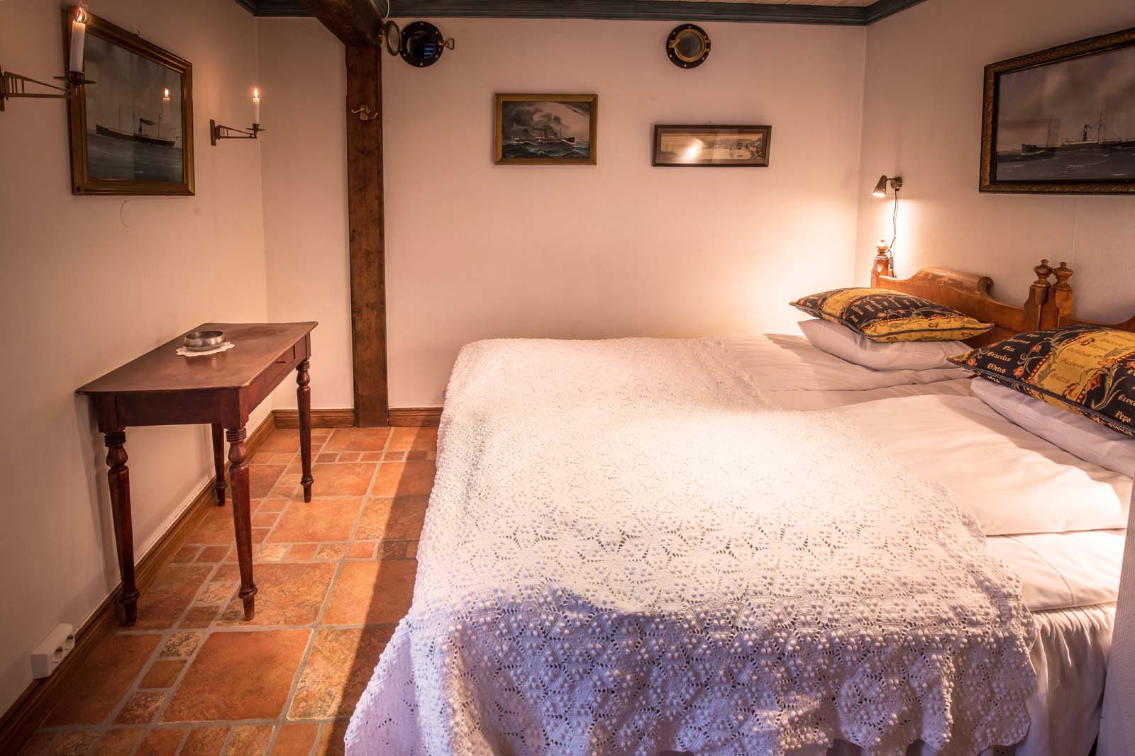 a bed with a white blanket and a table with a candle on it