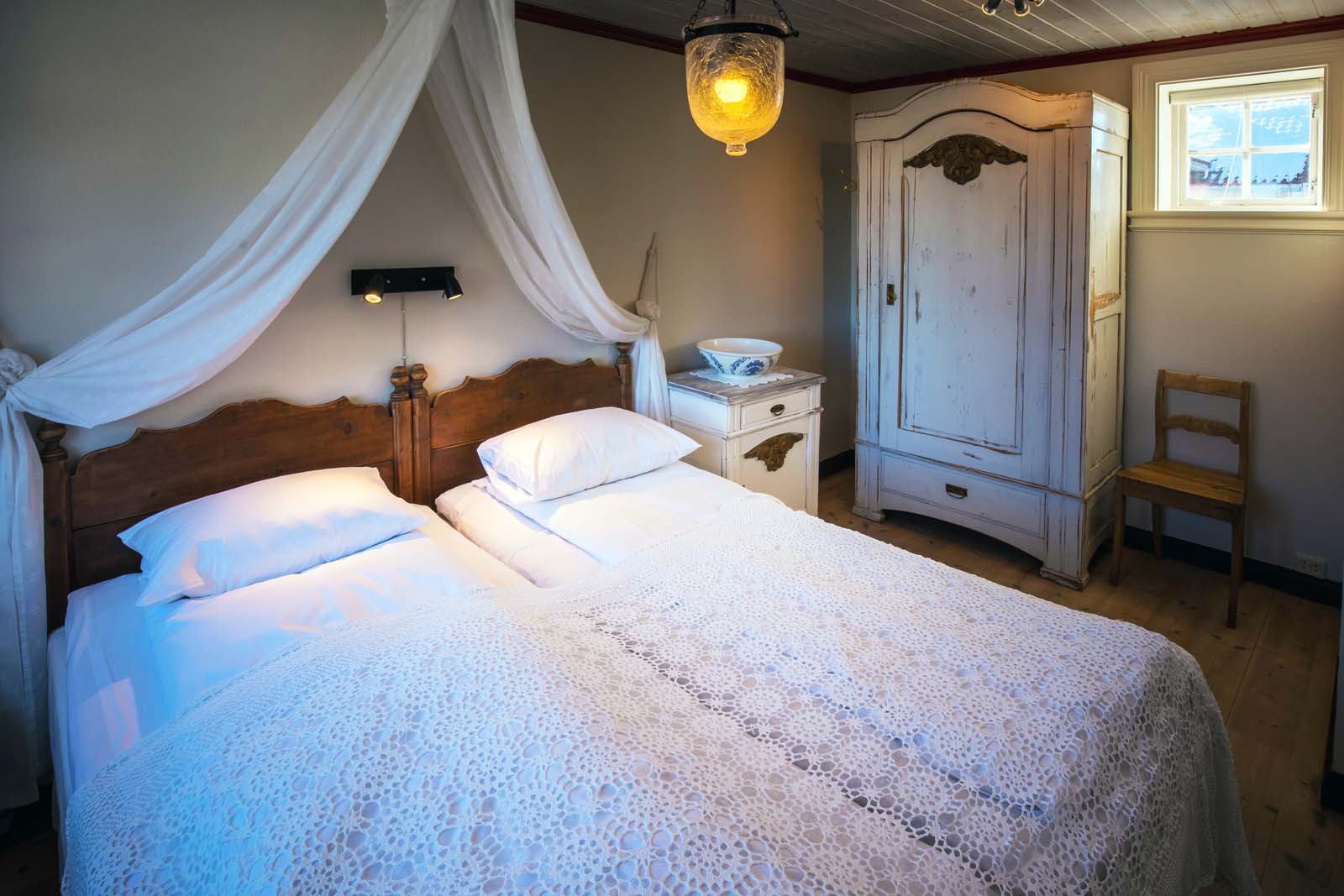 a bed with white sheets and a white dresser