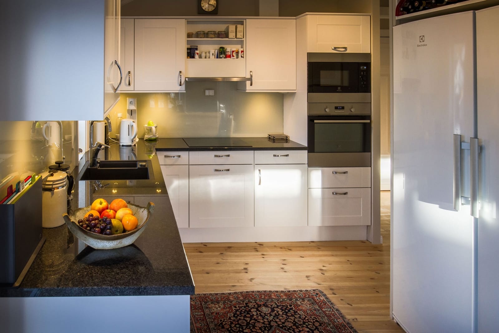 a kitchen with white cabinets and a bowl of fruit