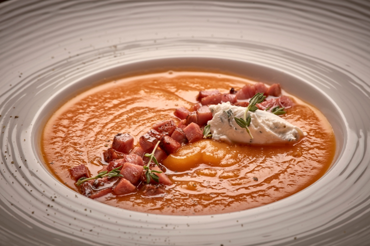 a bowl of soup with bacon and herbs