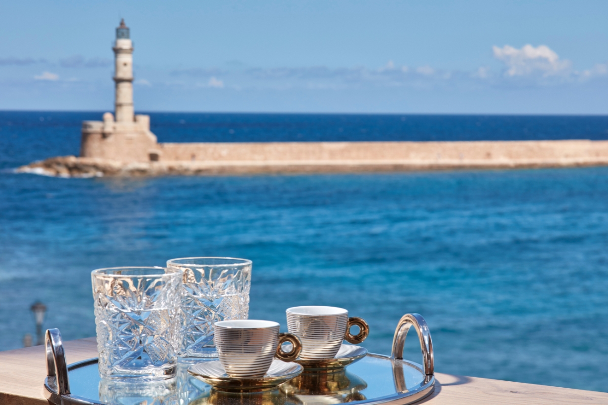a group of cups and glasses on a table with a lighthouse in the background