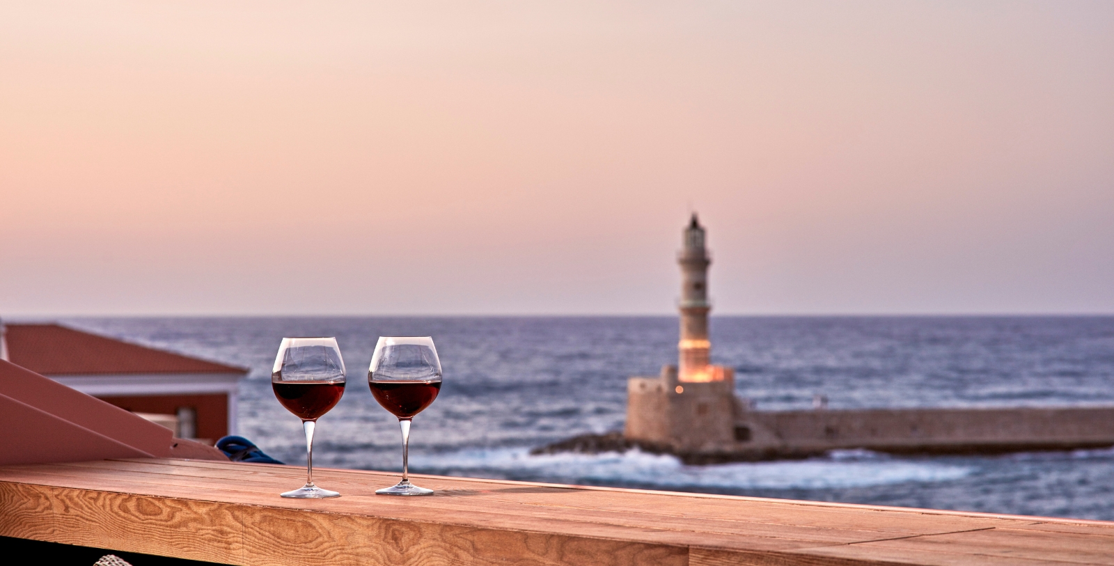 two glasses of wine on a wooden surface overlooking a body of water