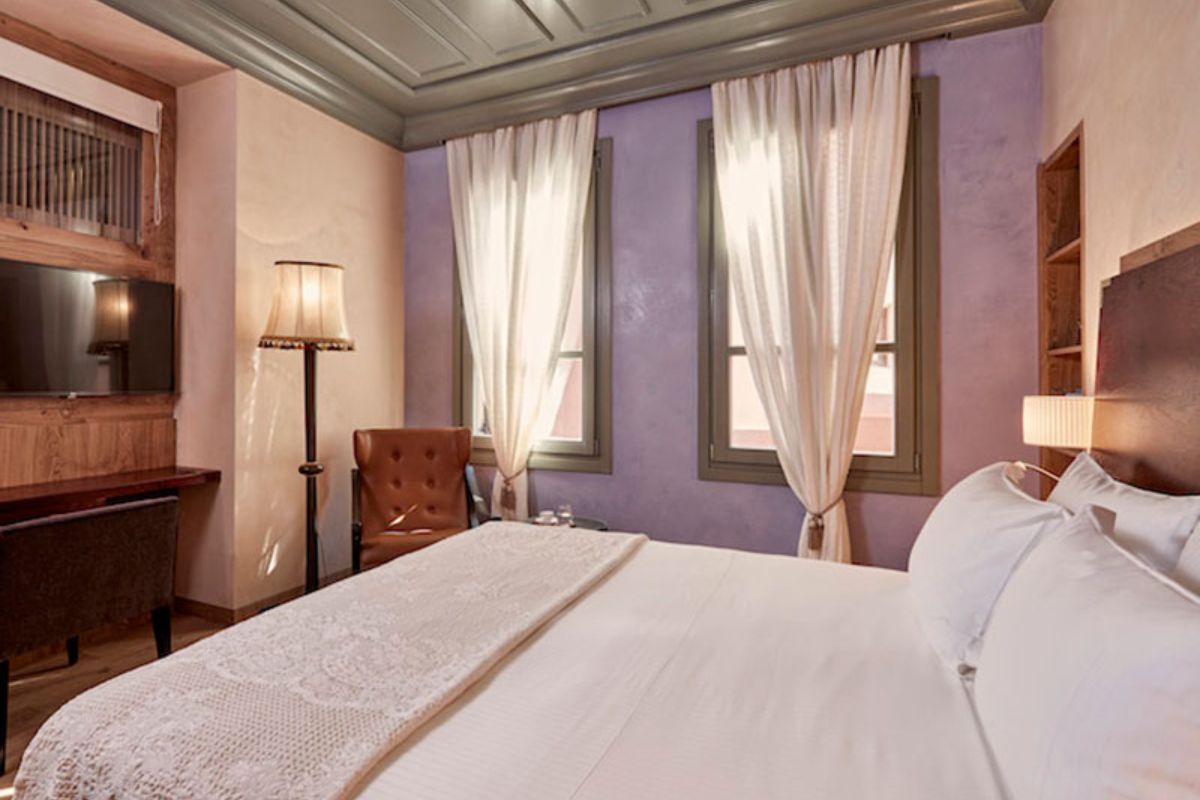 a bed with white sheets and a lamp in a room with purple walls