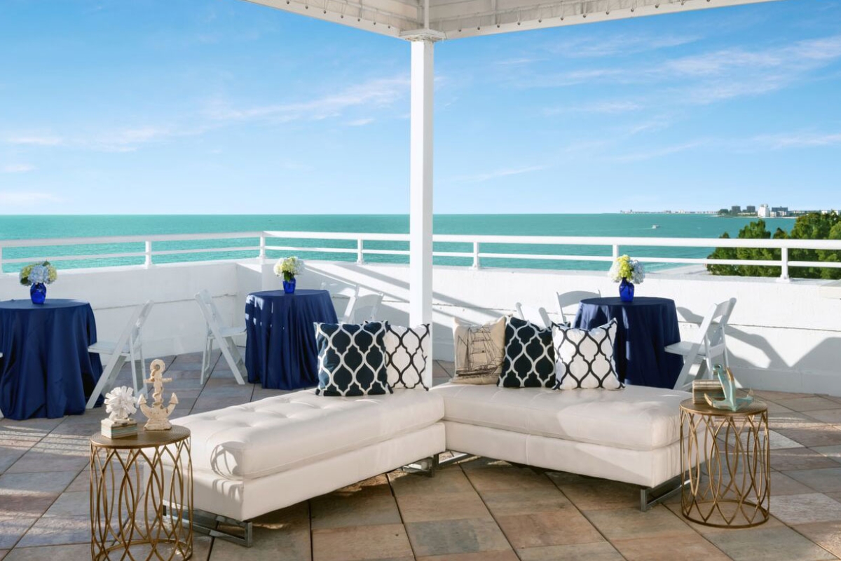 a white couches with blue and white pillows on a patio