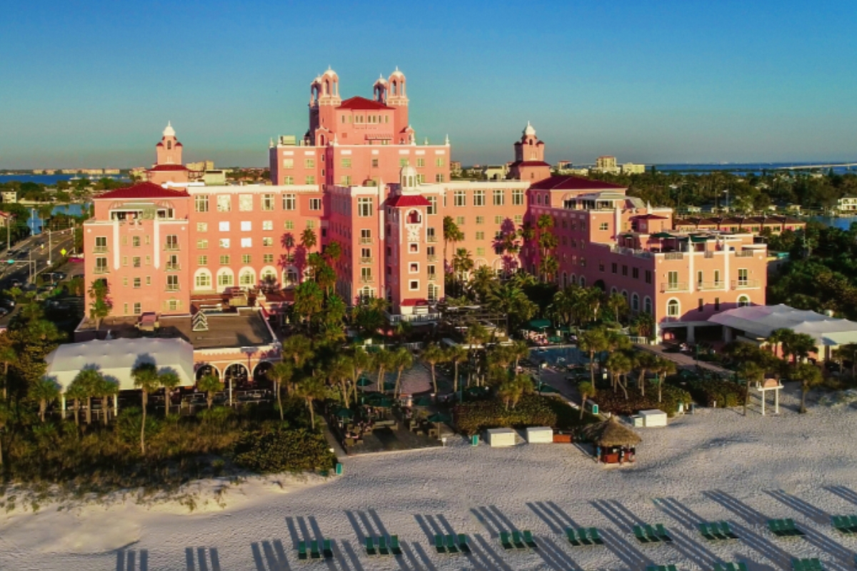 a large pink building with white sand and trees
