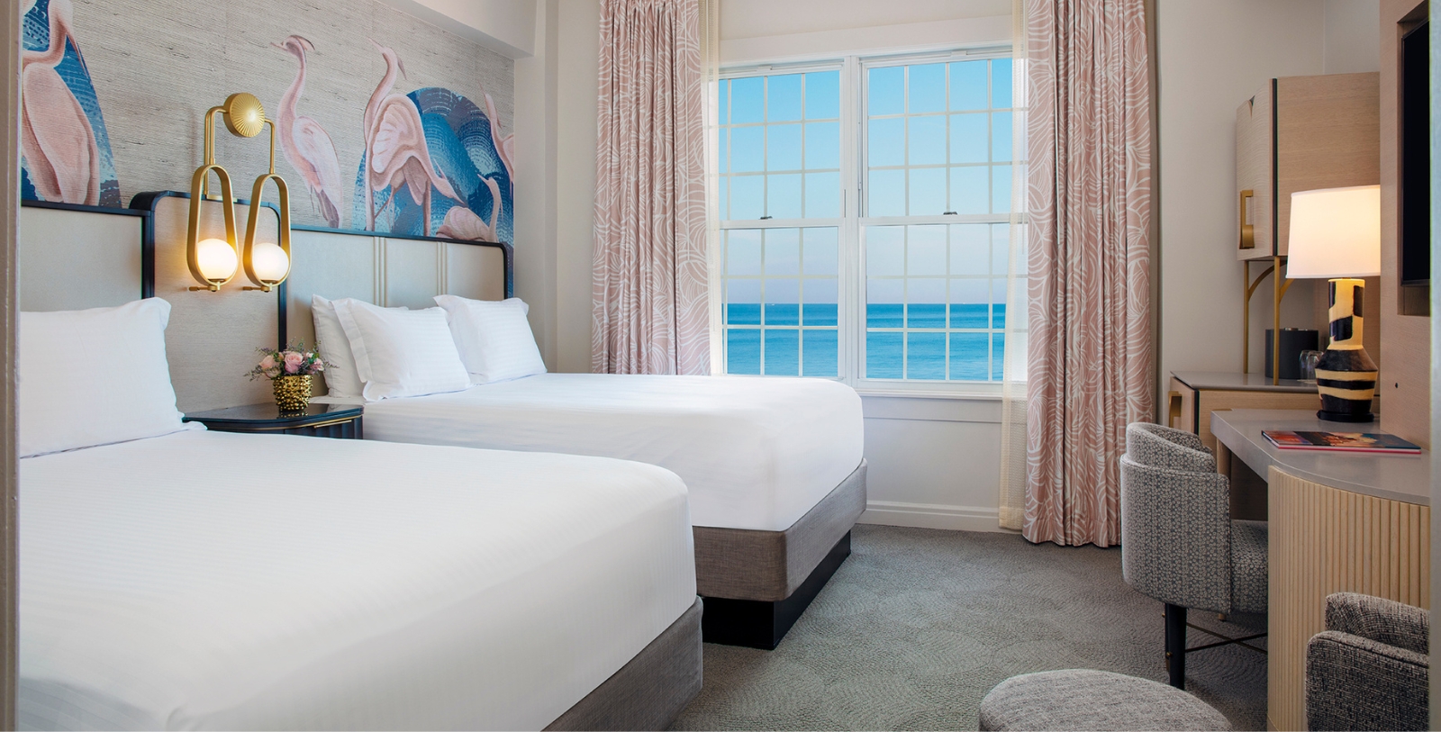 a room with two beds and a window with a view of the ocean