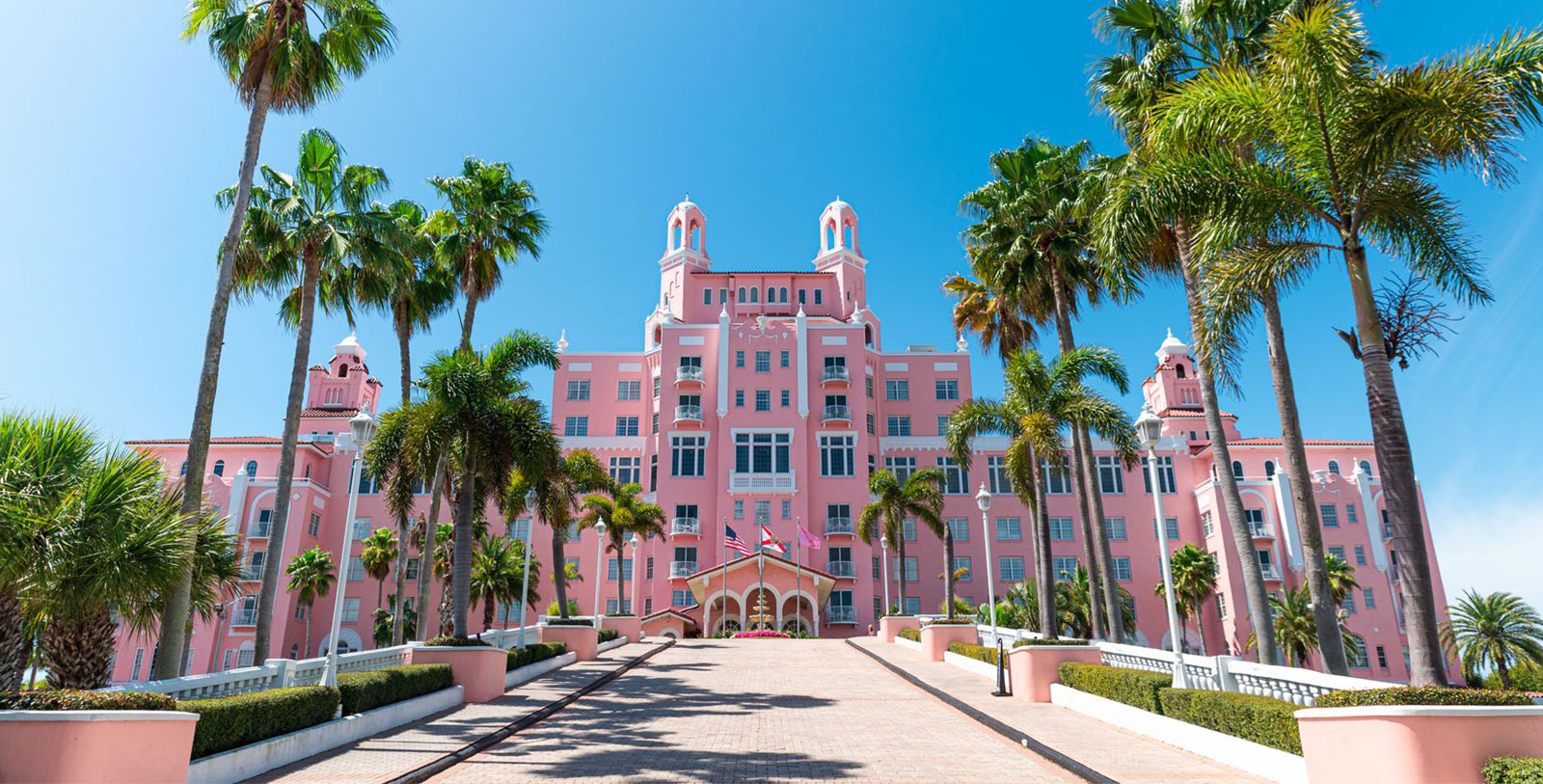 a pink building with palm trees with Don CeSar in the background