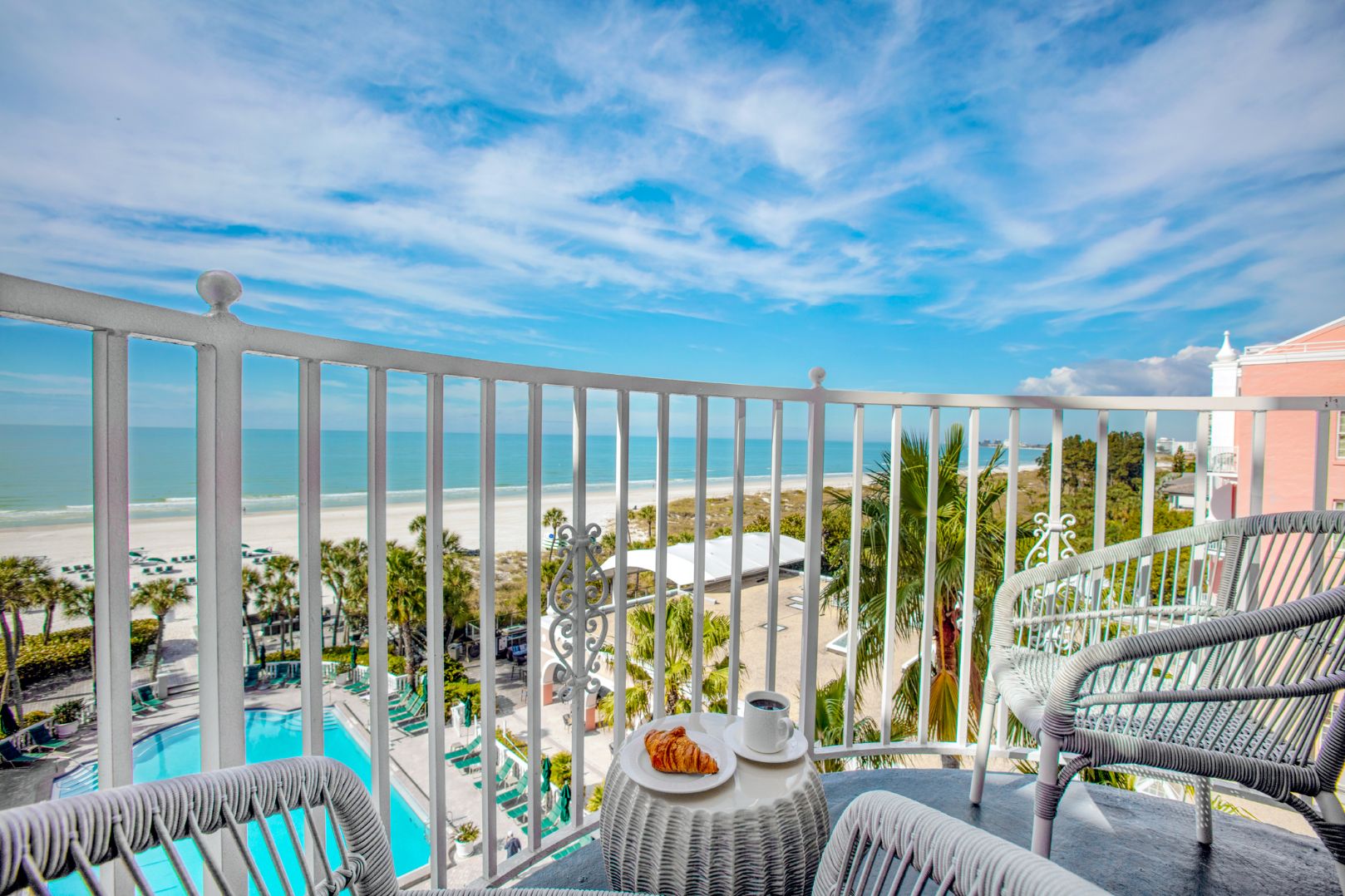 a balcony with a view of the beach and a table and chairs