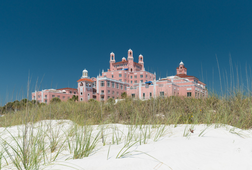 a pink building with white walls and a white roof with Don CeSar in the background