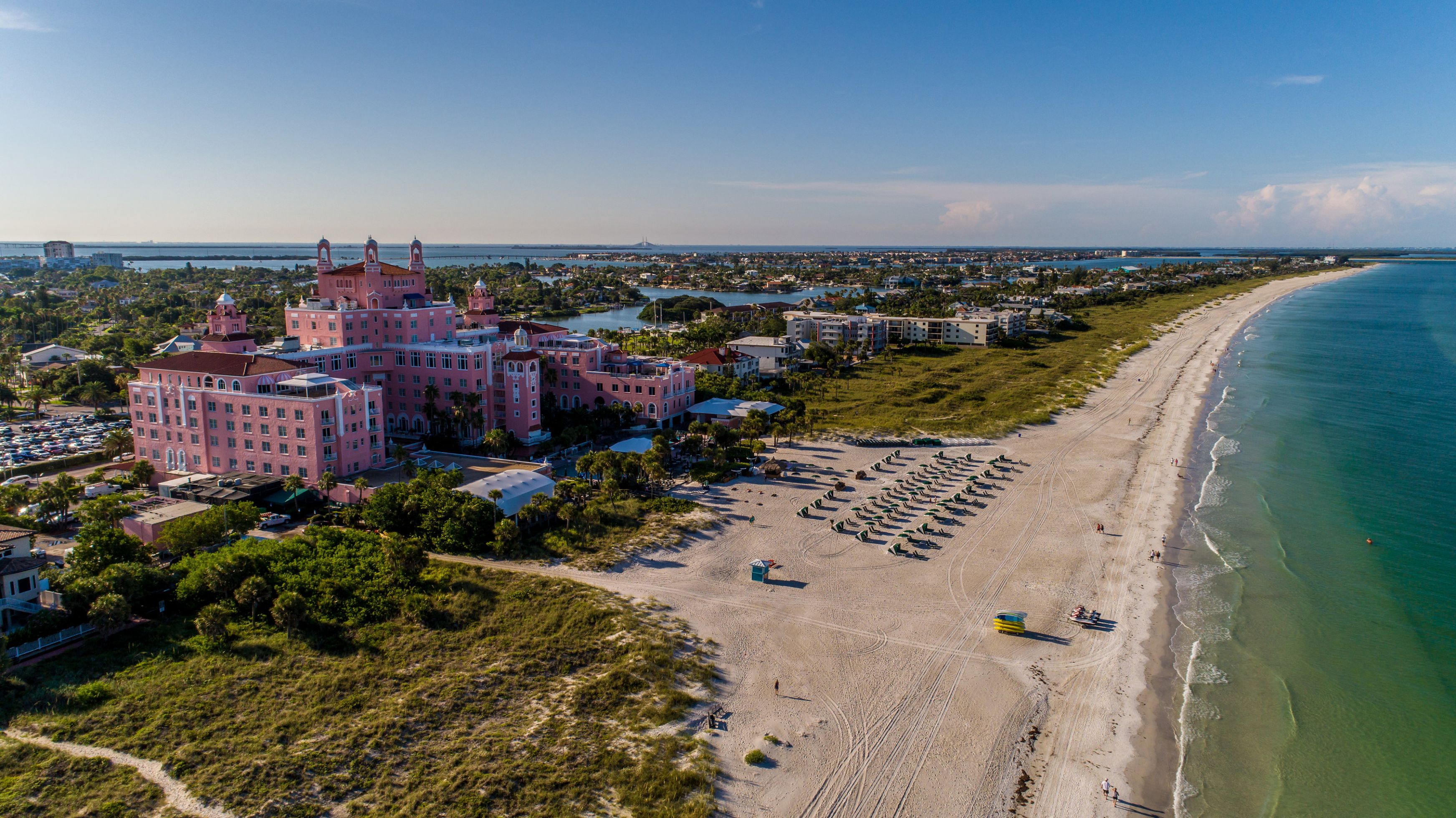 a beach with a pink building and many umbrellas