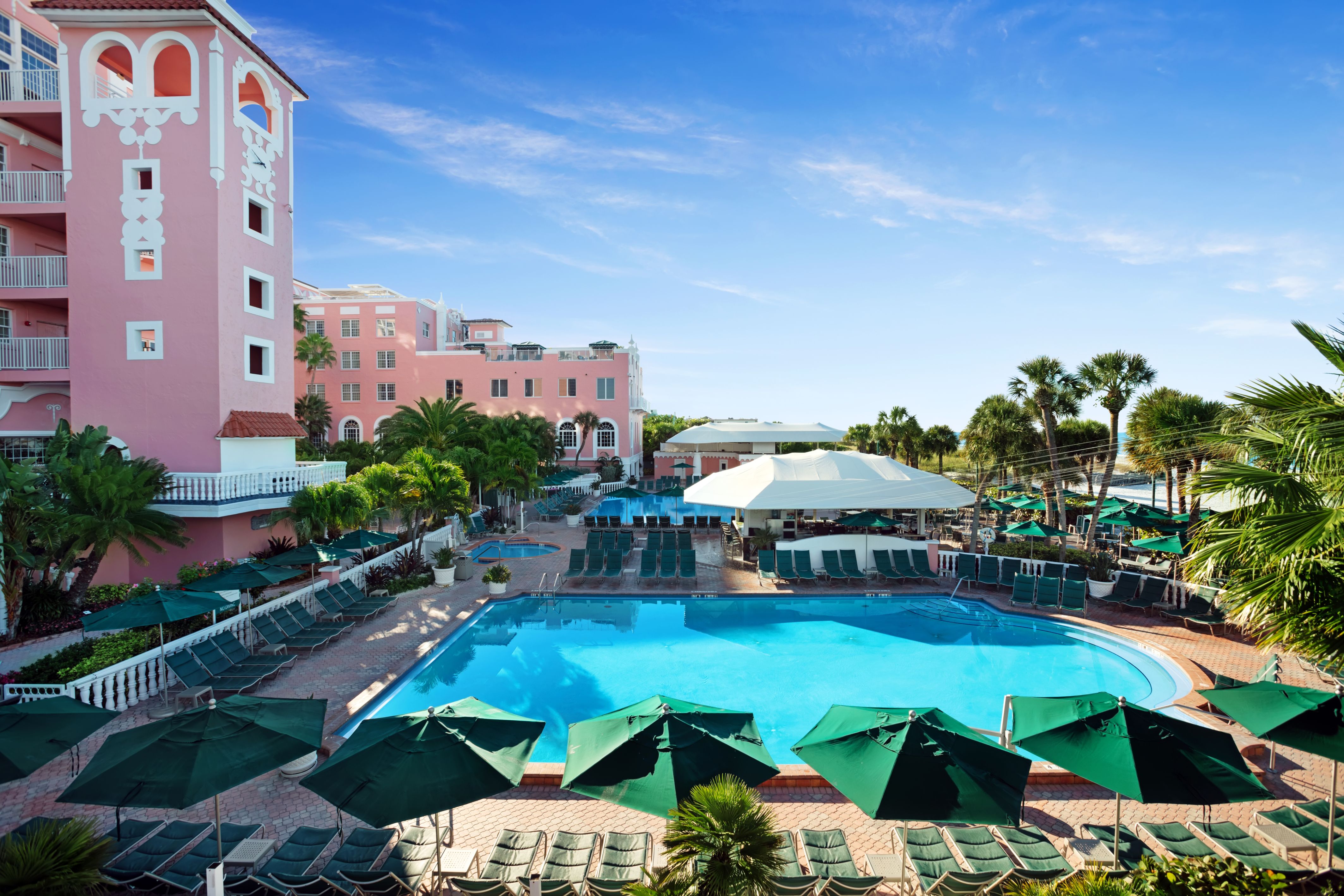 a pool with umbrellas and chairs in front of a building