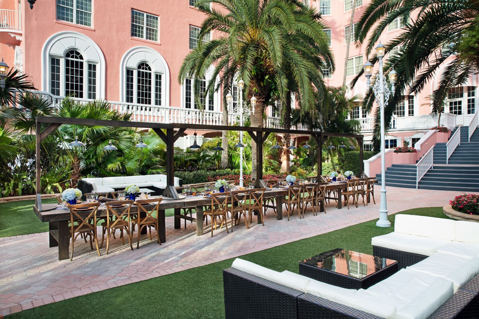 a long table set up in a courtyard with palm trees