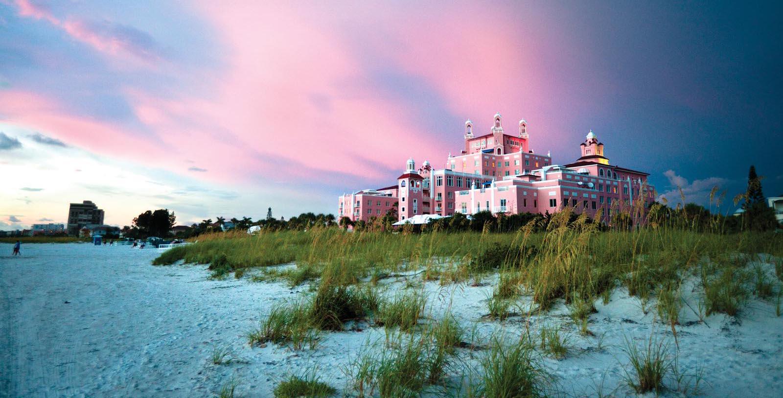 a pink building with towers and grass