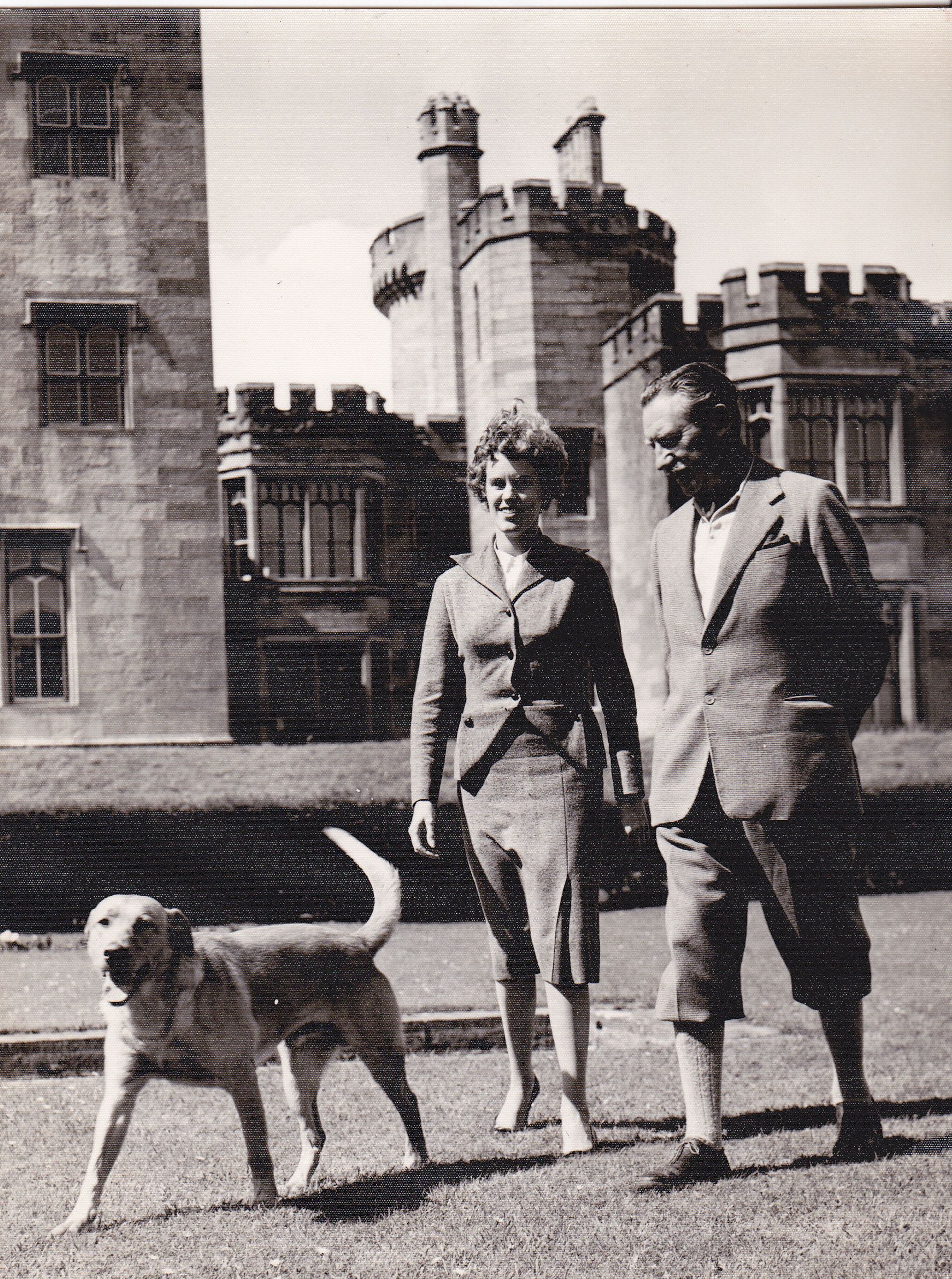 a man and woman standing next to a dog
