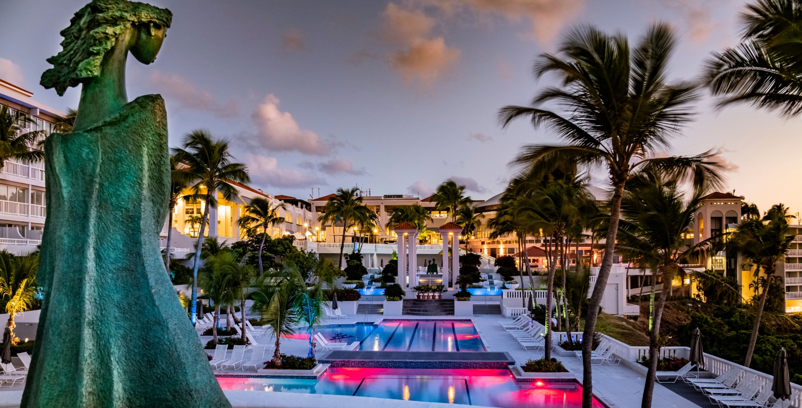 a pool with palm trees and buildings in the background