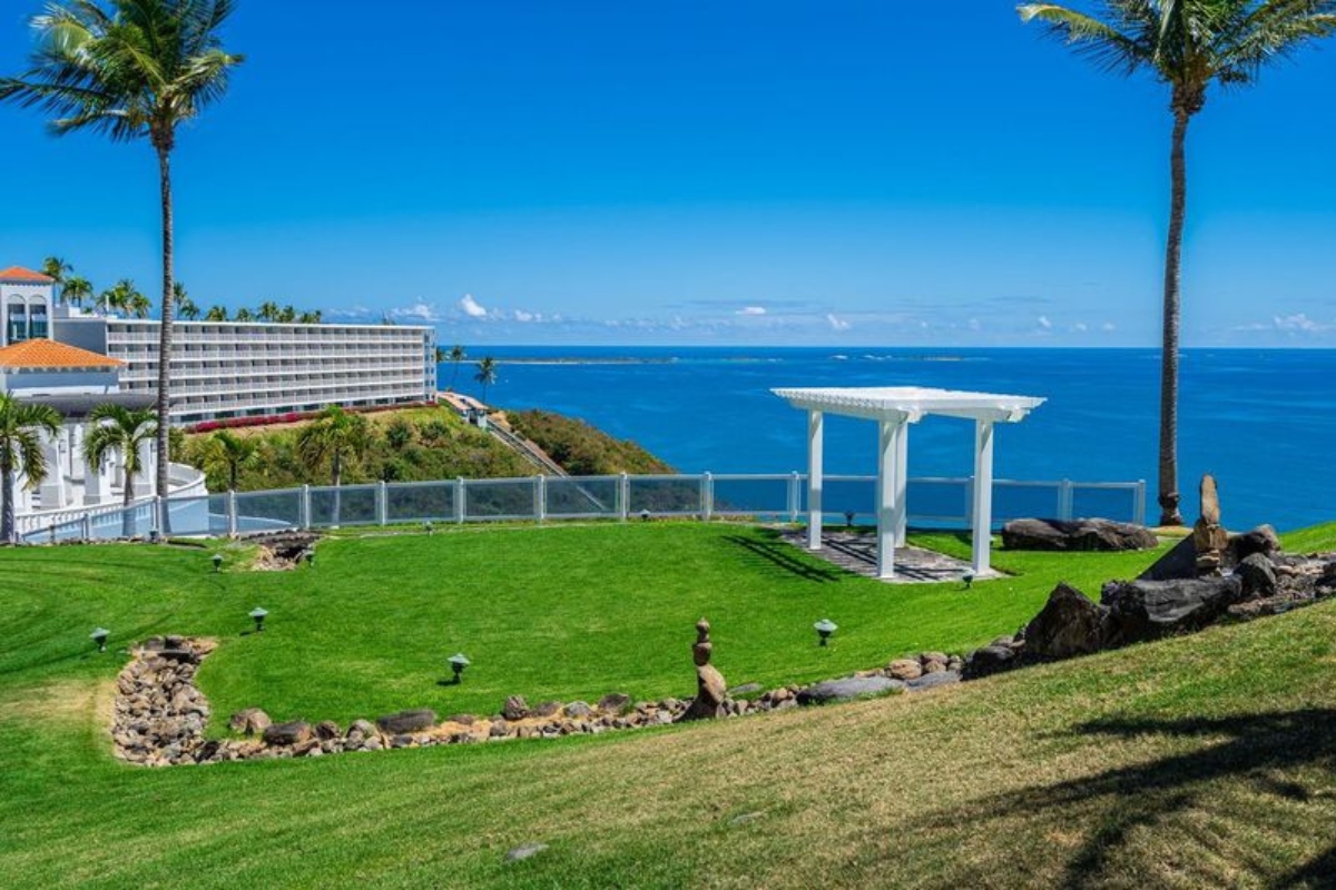 a white gazebo on a grassy area with a body of water in the background