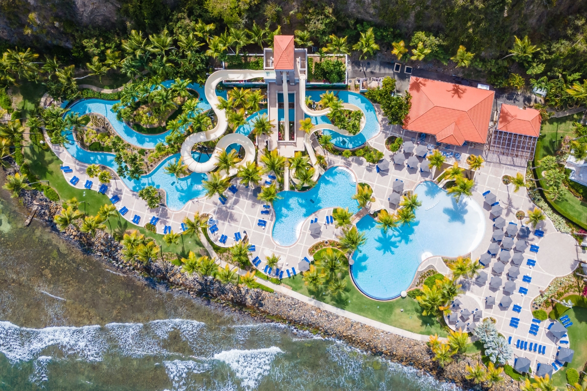 a swimming pool and water slide by a body of water