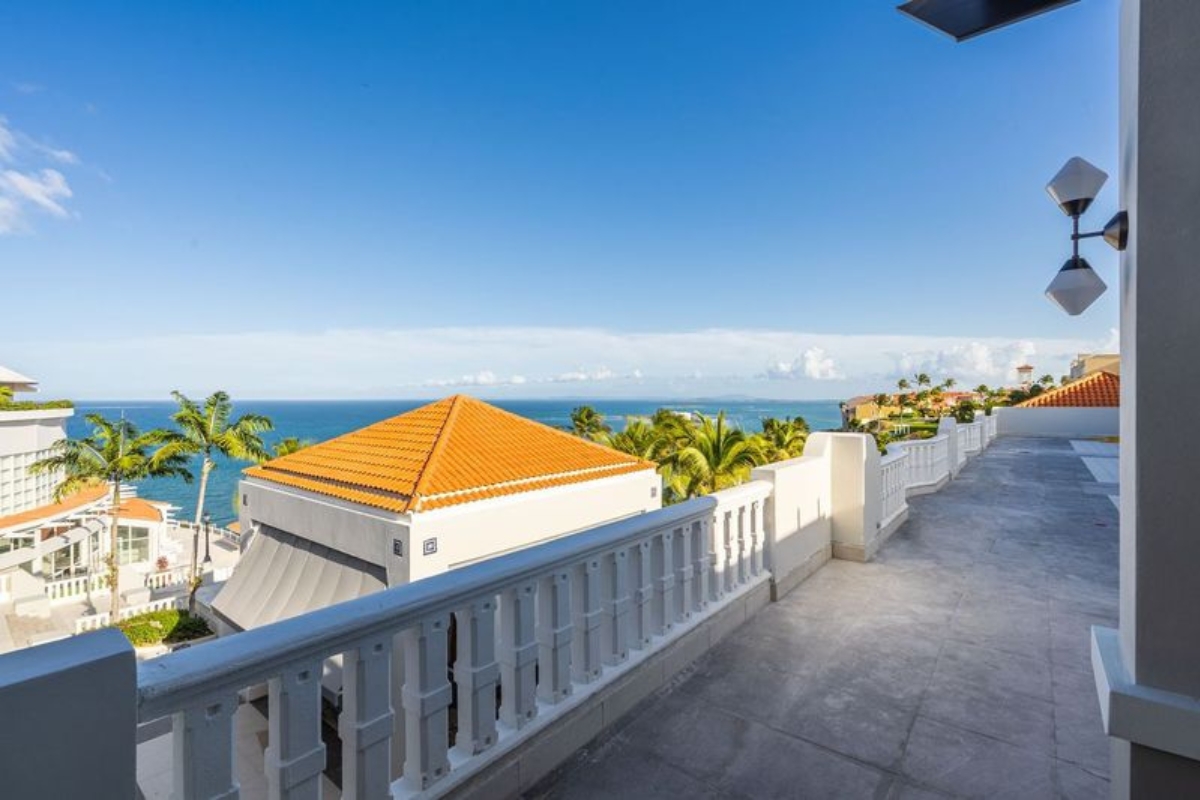 a walkway with a white railing and a building with orange roof
