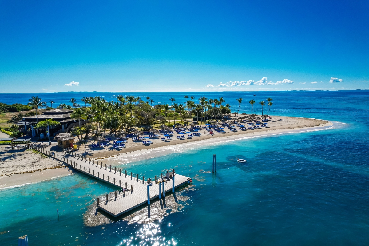 a dock on a beach with palm trees and a beach with a building and a beach
