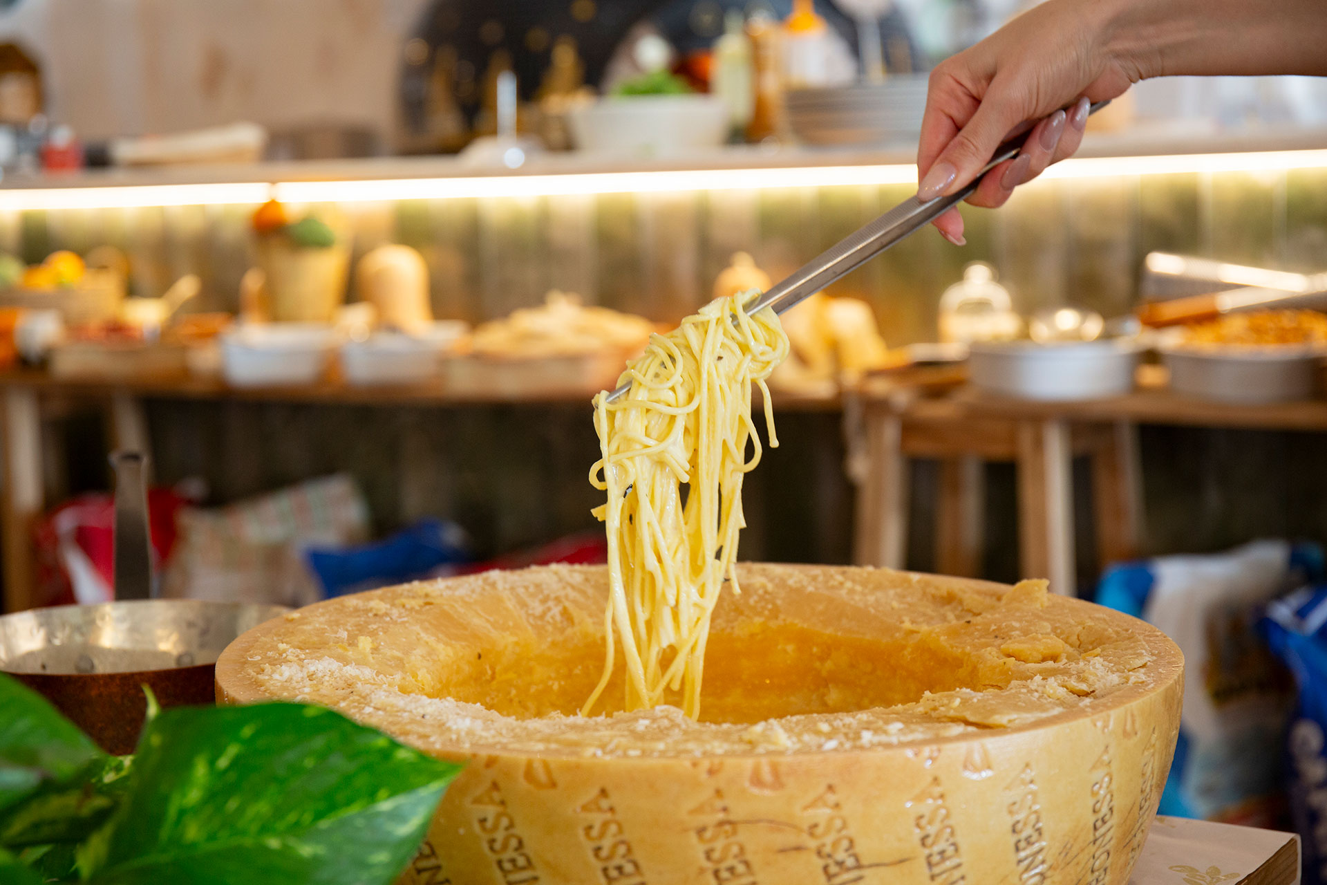 a person holding a pair of noodles over a cheese fondue