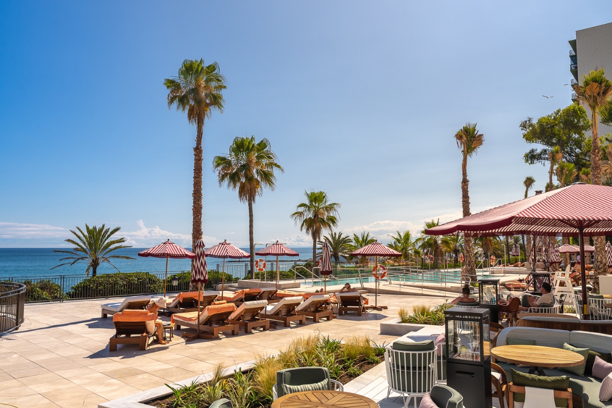 a pool with chairs and umbrellas and palm trees