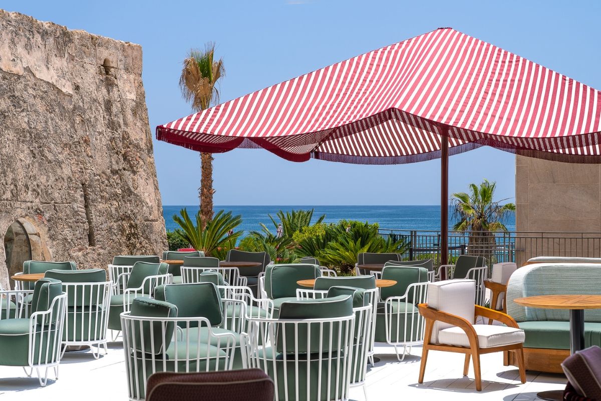 a red and white striped umbrella over chairs and tables