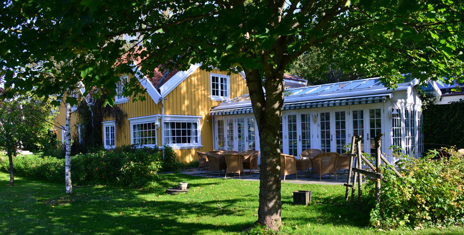 a yellow house with chairs and trees