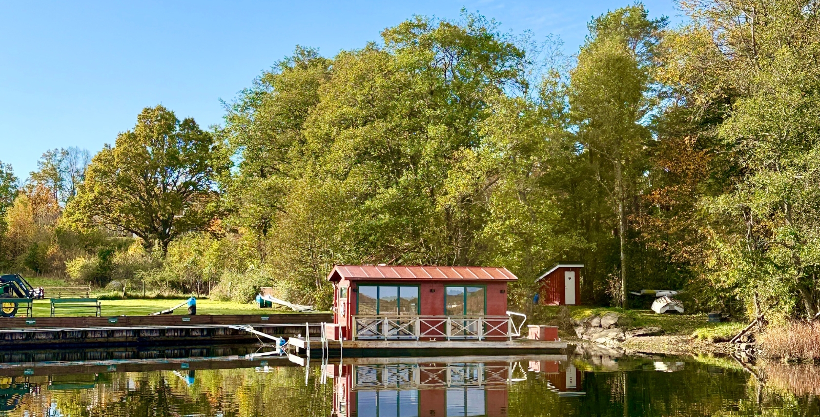 a small red building on a dock on a lake